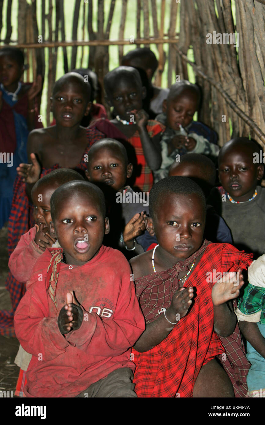 Maasai pre-schoolers in a classroom made with reeds clapping hands and singing Stock Photo