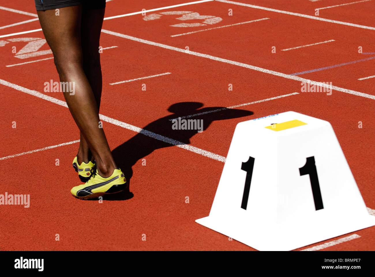 legs of a male sprinter next to starting block number one on athletic track outside Stock Photo
