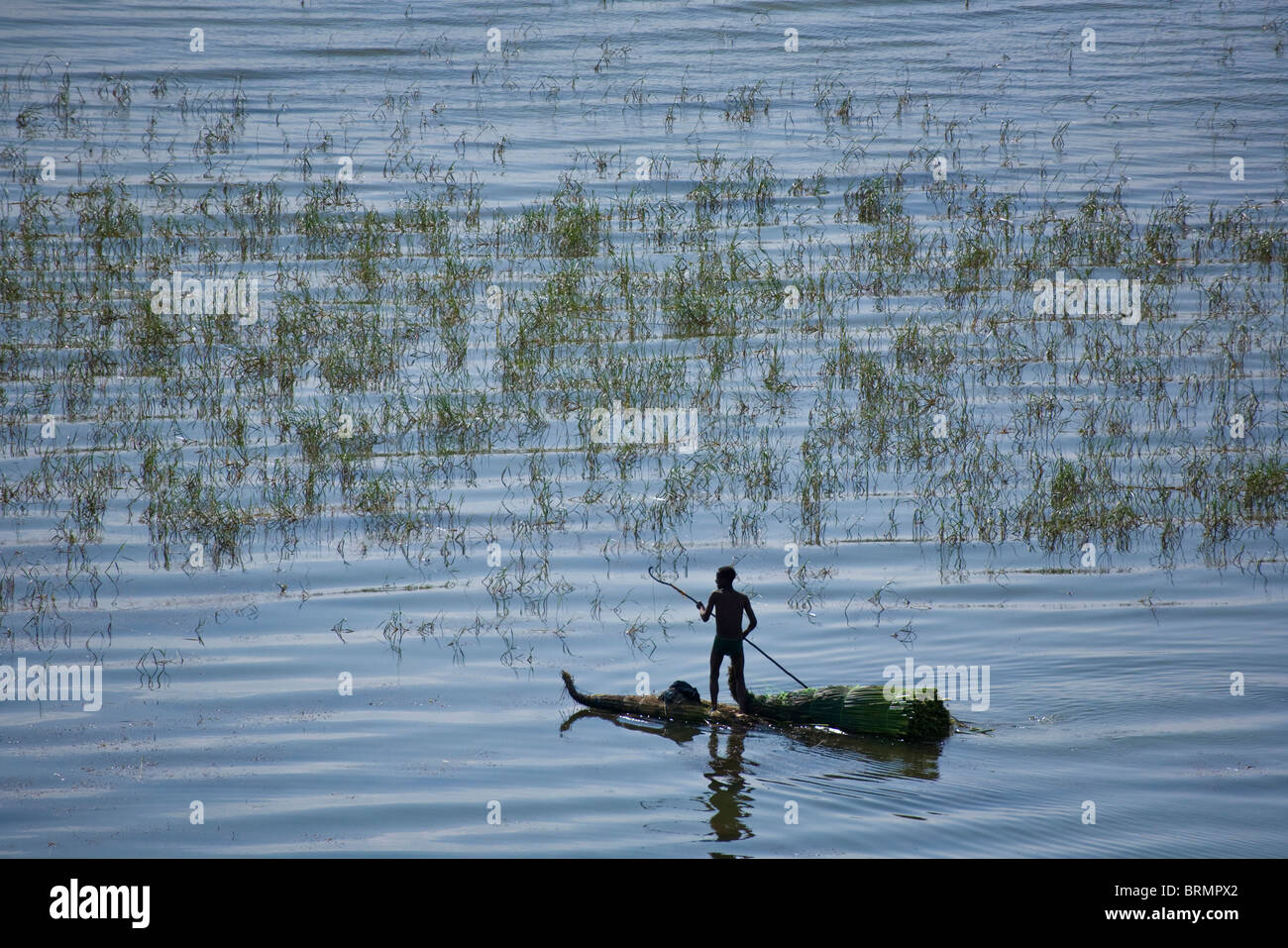 Fisherman poling along on a traditional papyrus raft Stock Photo
