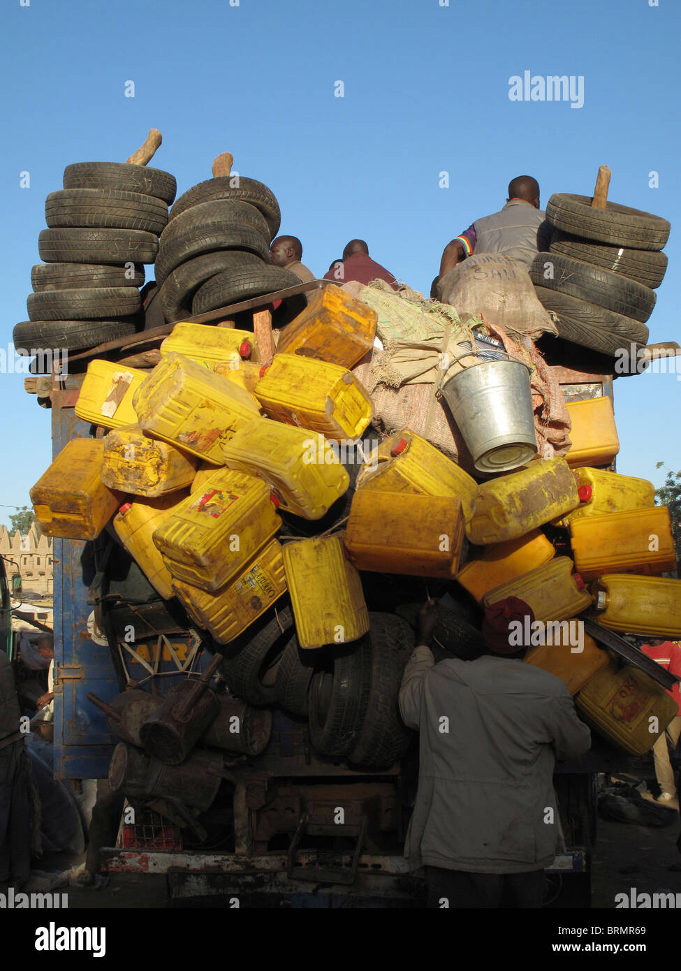 Man loading plastic jerry cans and tyres onto the back of a  truck Stock Photo