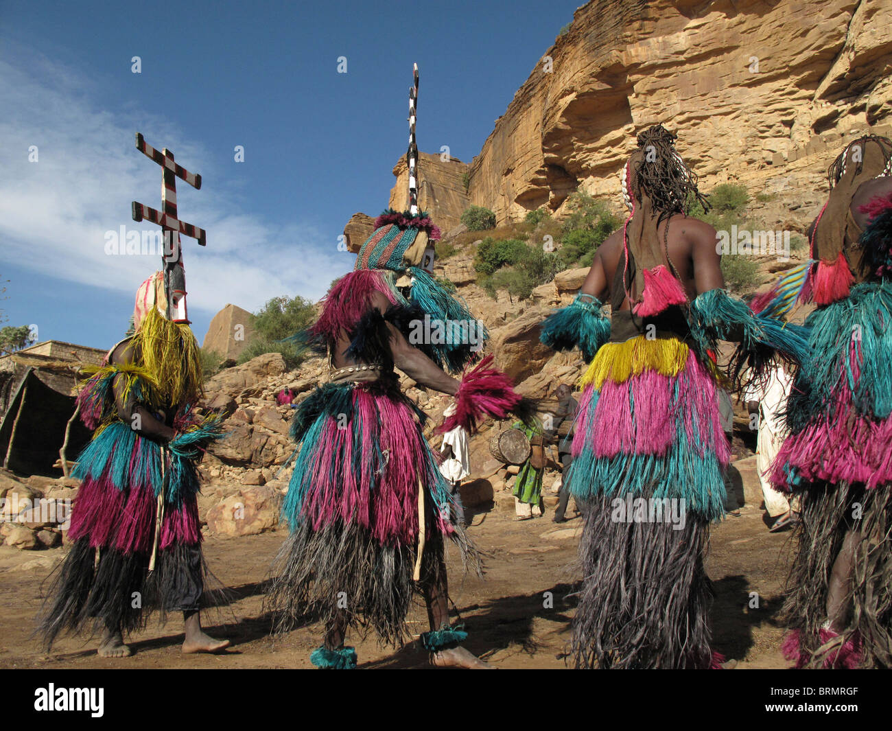 Dogon dancers wearing masks and long colourful straw skirts performing a ceremonial dance Stock Photo