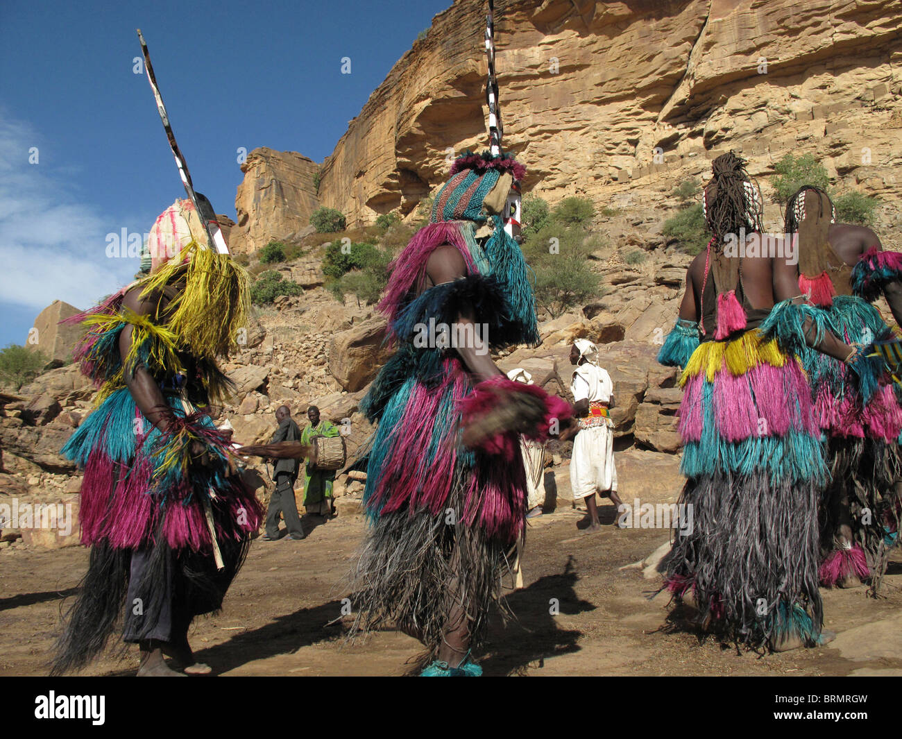 Dogon dancers wearing masks and long colourful straw skirts performing a ceremonial dance Stock Photo