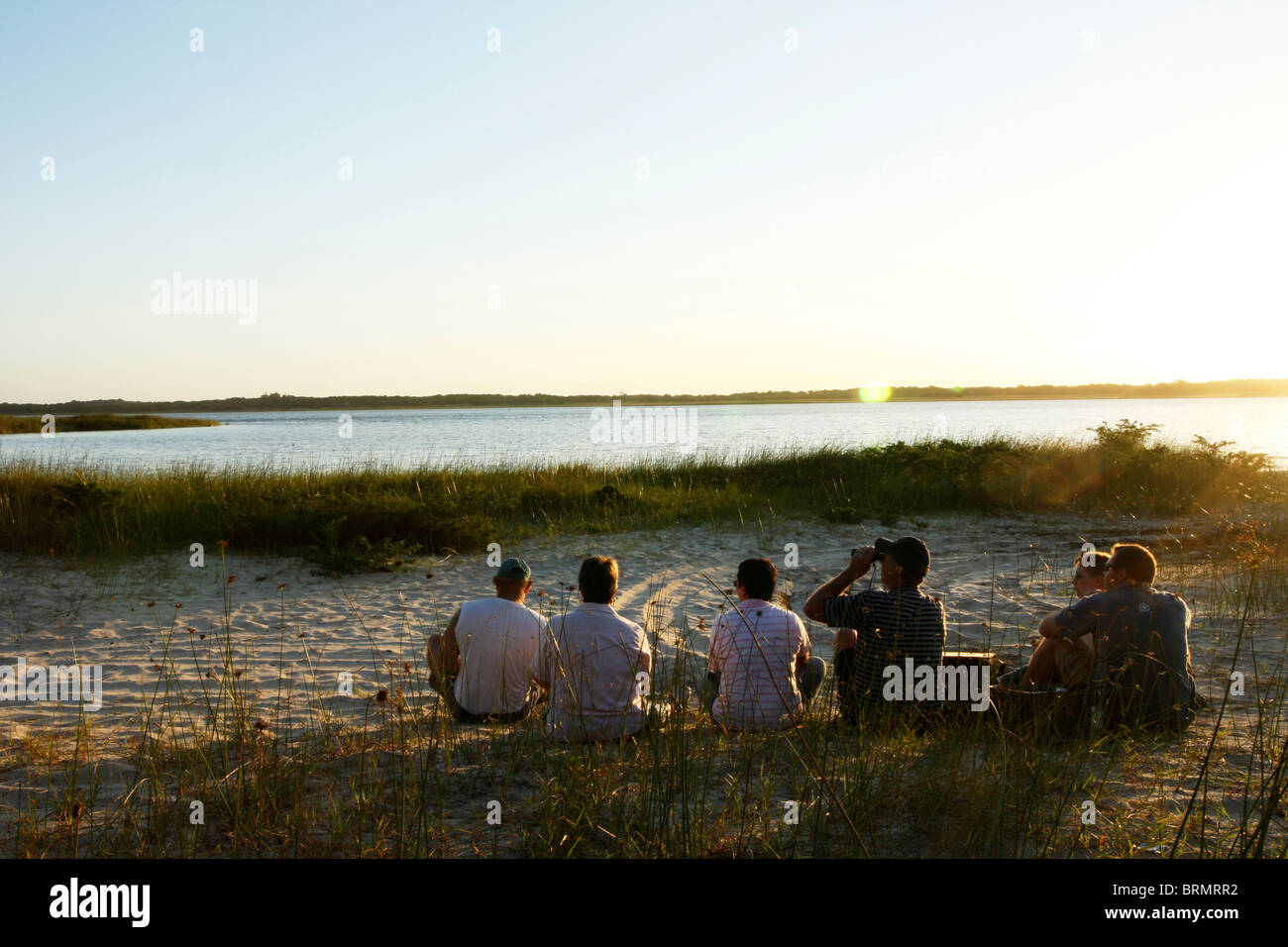 Group of tourists resting on a river bank Stock Photo