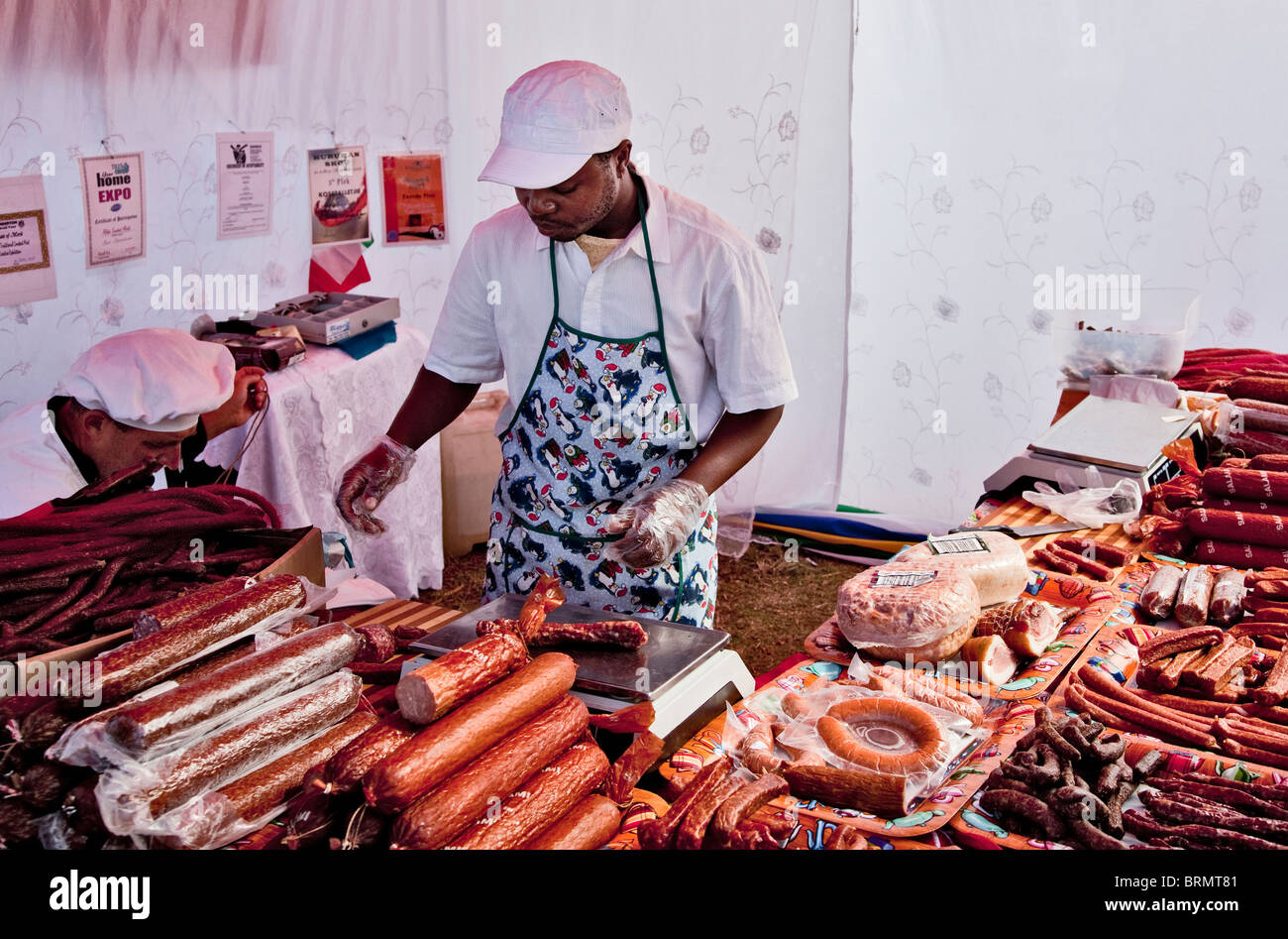 Man weighing salami at a market stall selling cured meat Stock Photo