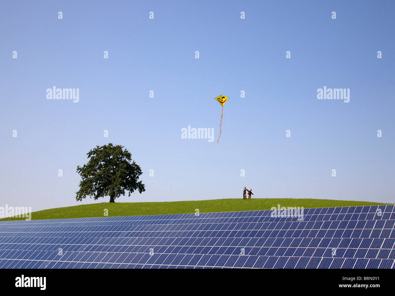 Boys flying kite at solar power station Stock Photo Alamy