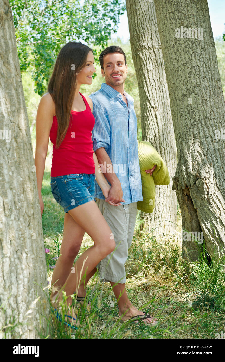 Couple walking hand-in-hand in forest Stock Photo