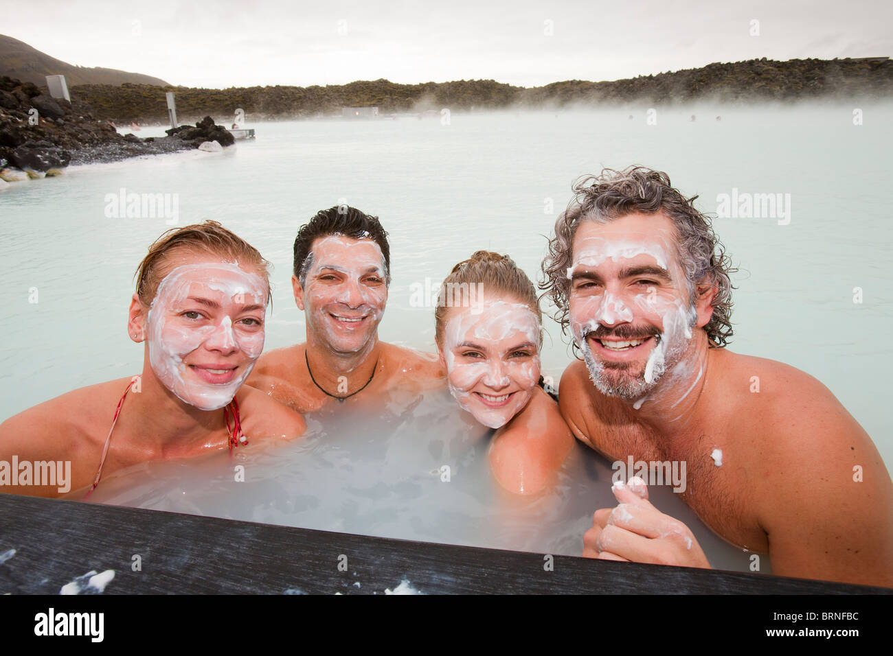 Four friends relax at the Blue Lagoon near at Keflavik in Iceland. Stock Photo