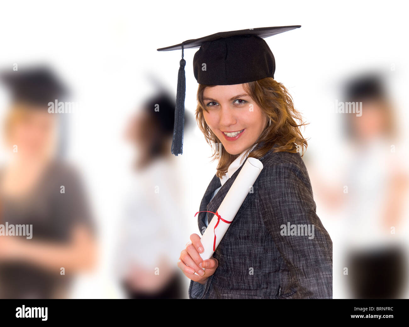 Young women after graduation with diploma in right hand, other students blurry in background Stock Photo