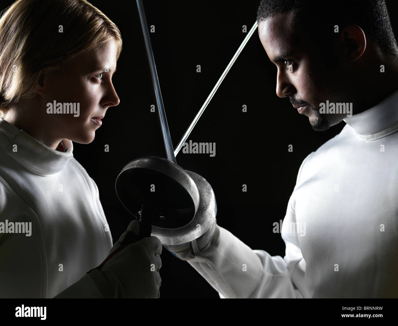 License available at MaximImages.com - Two fencers, a young woman and a young man, confronting each other with their fencing epees crossed Stock Photo
