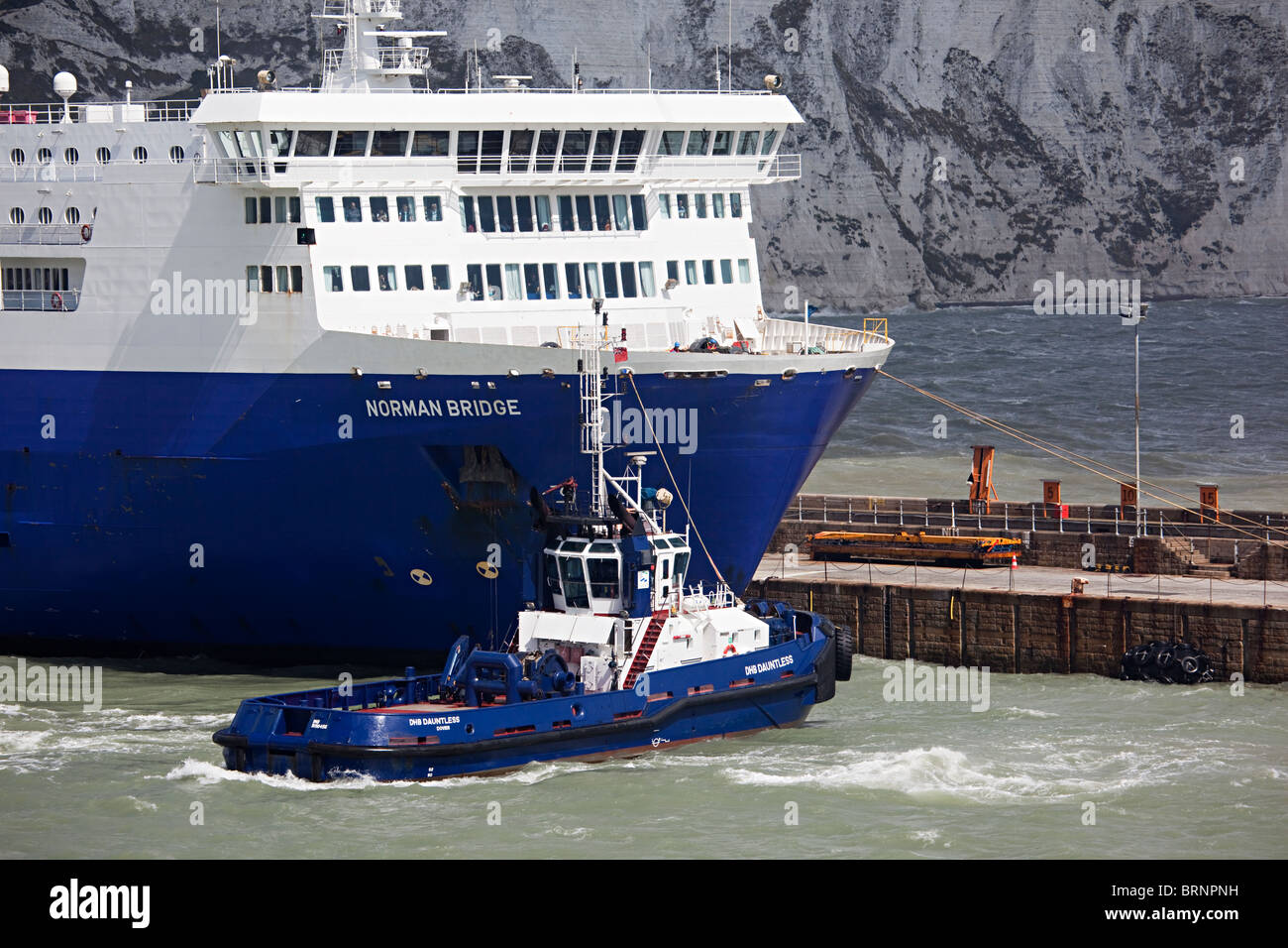 Tugboat pulling out LD Lines cross channel ferry the Norman Bridge from Dover harbour England UK Stock Photo