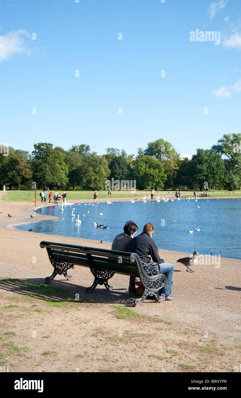 Young  couple sitting on a bench at Kensington Gardens, London, UK Stock Photo