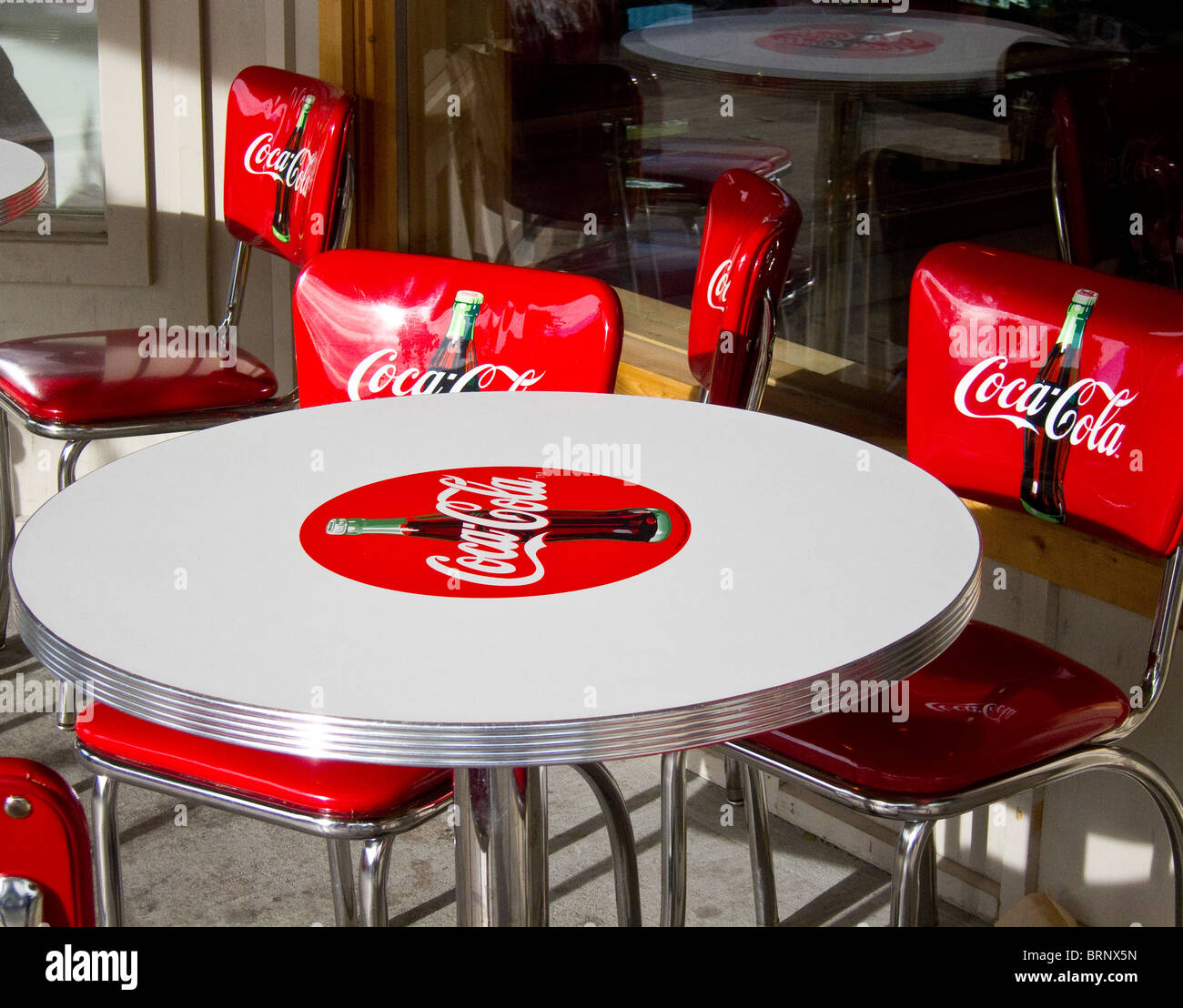 Red coca cola chairs around a white coca cola table Stock Photo - Alamy