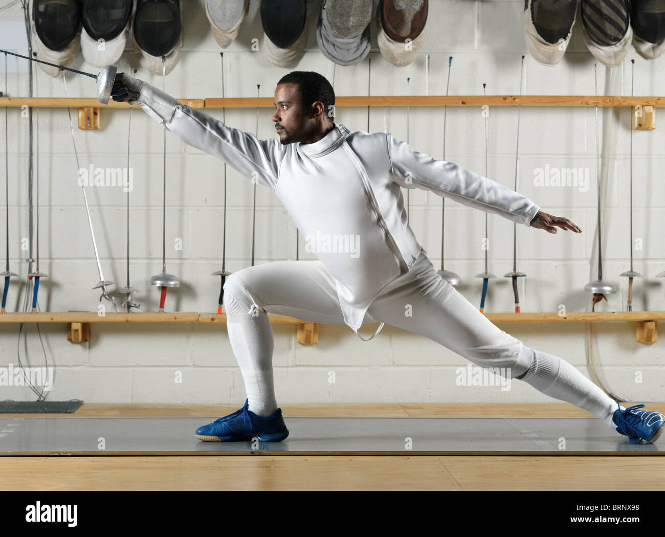 Fencer in white fencing uniform practicing in a gym Stock Photo - Alamy