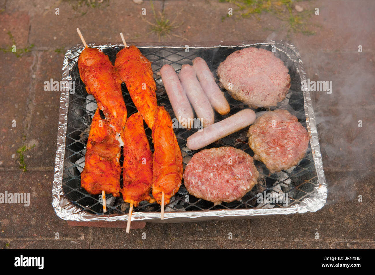 Disposable BBQ with Burgers Chicken Sausages Stock Photo Alamy