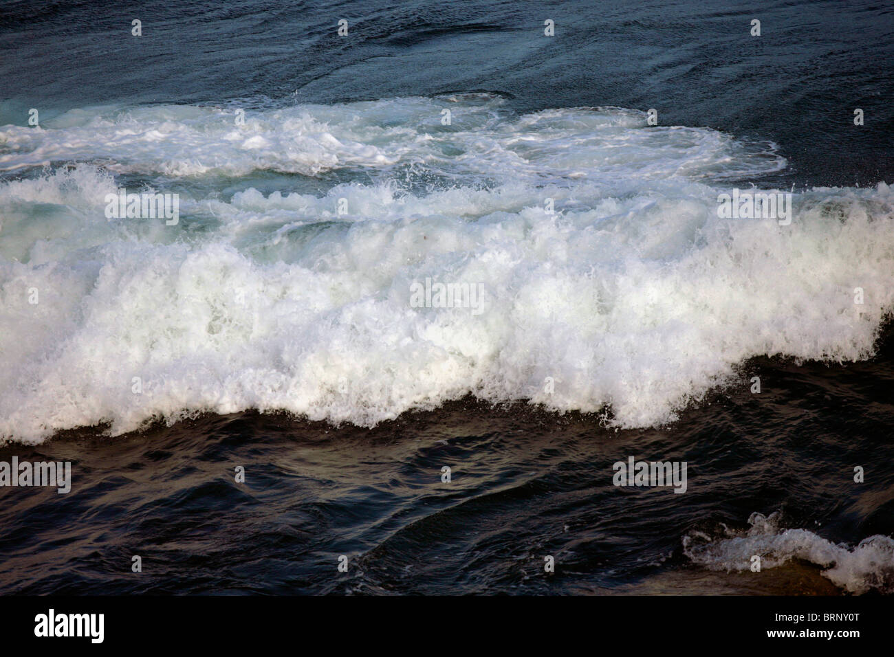 wave waves crashing shore rocks beach uk sea water Stock Photo