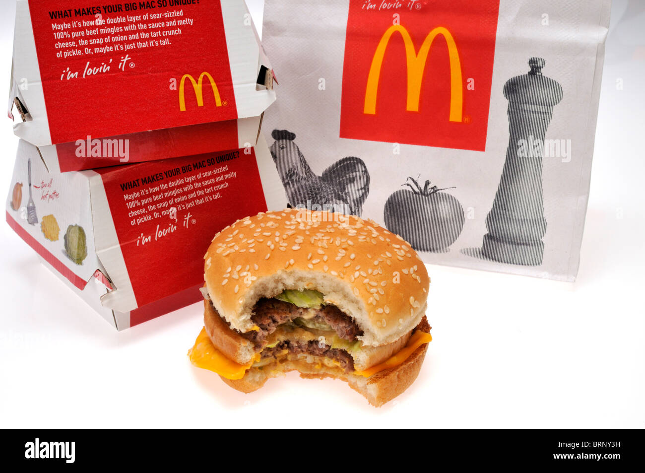 McDonald's bag with a Big Mac that has a bite taken out of it & take-out container on white background cut out. Stock Photo