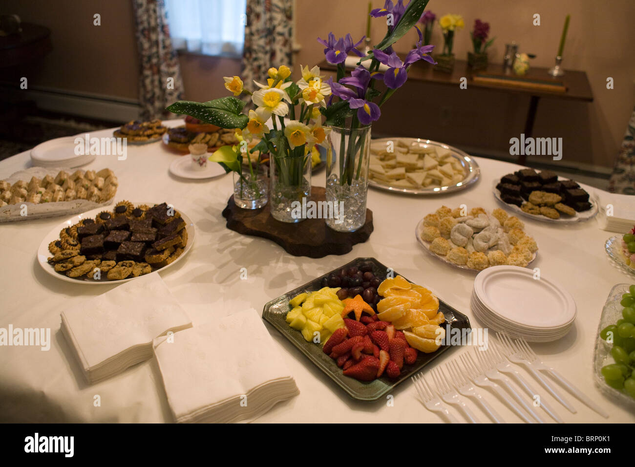 Ladies' tea table set with flowers, fruit, sandwiches, and cookies Stock Photo