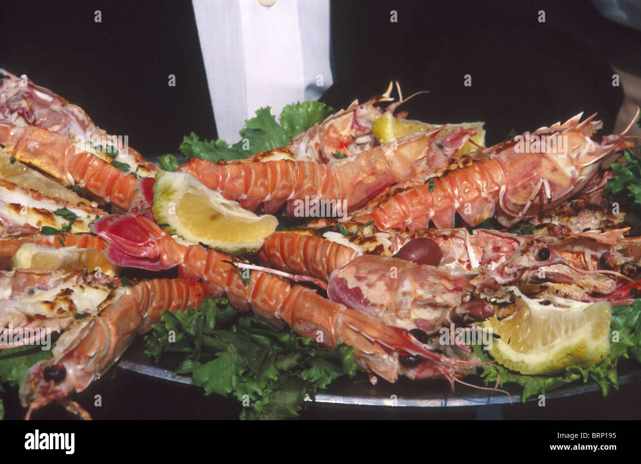 A selection of tiger prawns is presented on a platter with slices of lemon at a Mozambiquan Restaurant Stock Photo