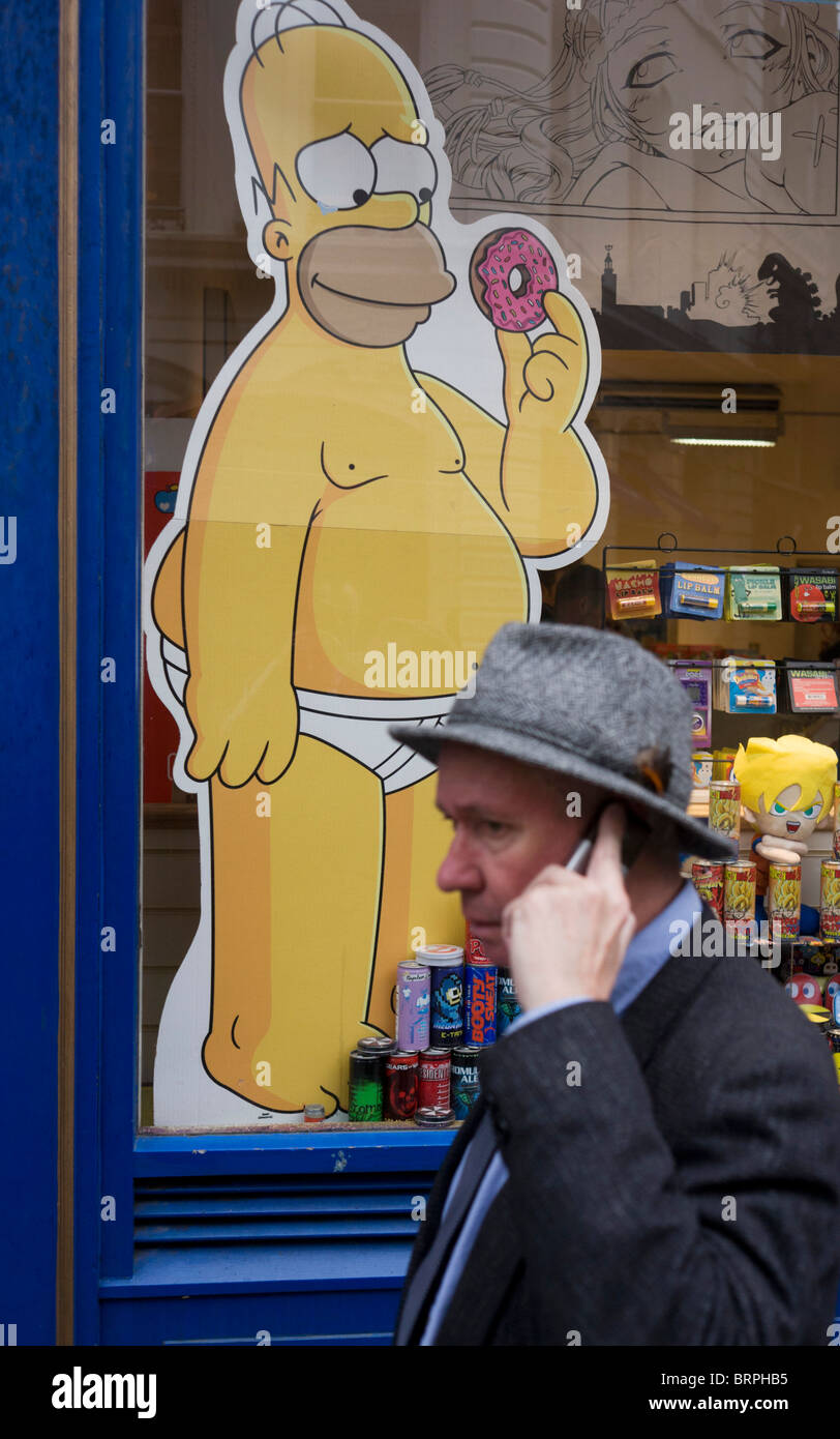 Homer Simpson cartoon character and passer-by holding mobile phone in central London. Stock Photo