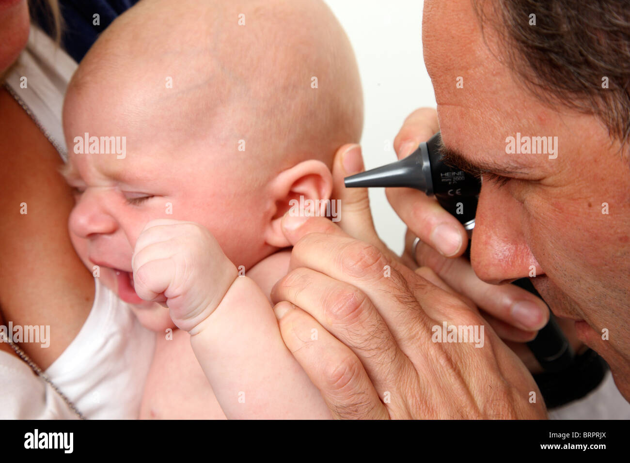Doctor's surgery, paediatrician. Mother and baby. Medical examination of a 4 month old newborn. Checking the ear, auditory canal Stock Photo