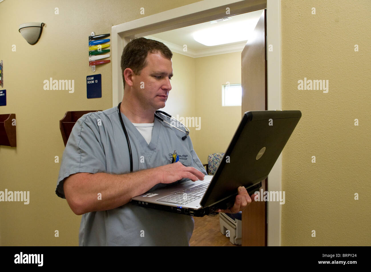 Male nurse practitioner  in Victoria, Texas reviews patient information on laptop computer before entering examining room. Stock Photo