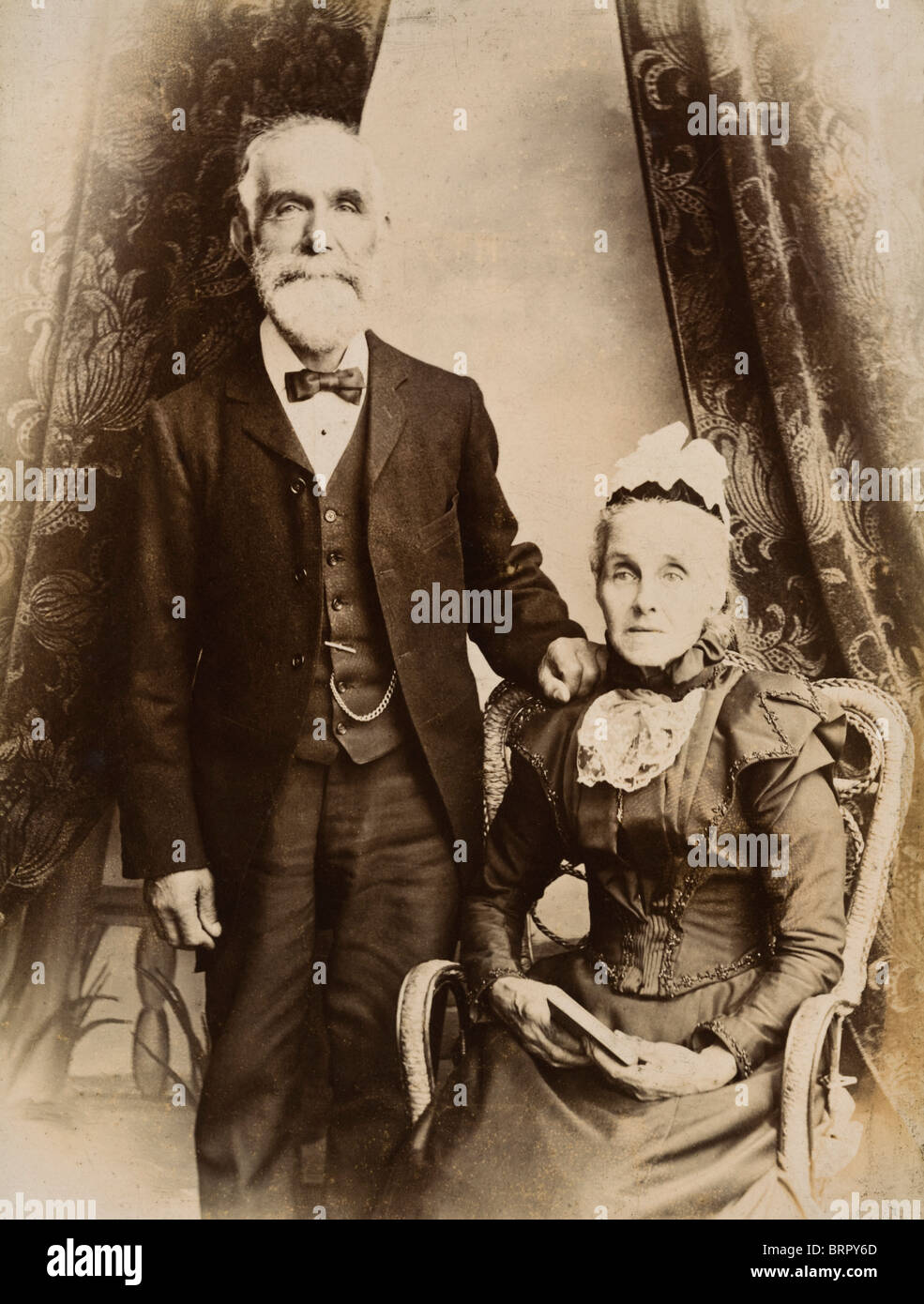 Elderly Victorian couple husband and wife pose in a photographers studio circa 1880 Stock Photo