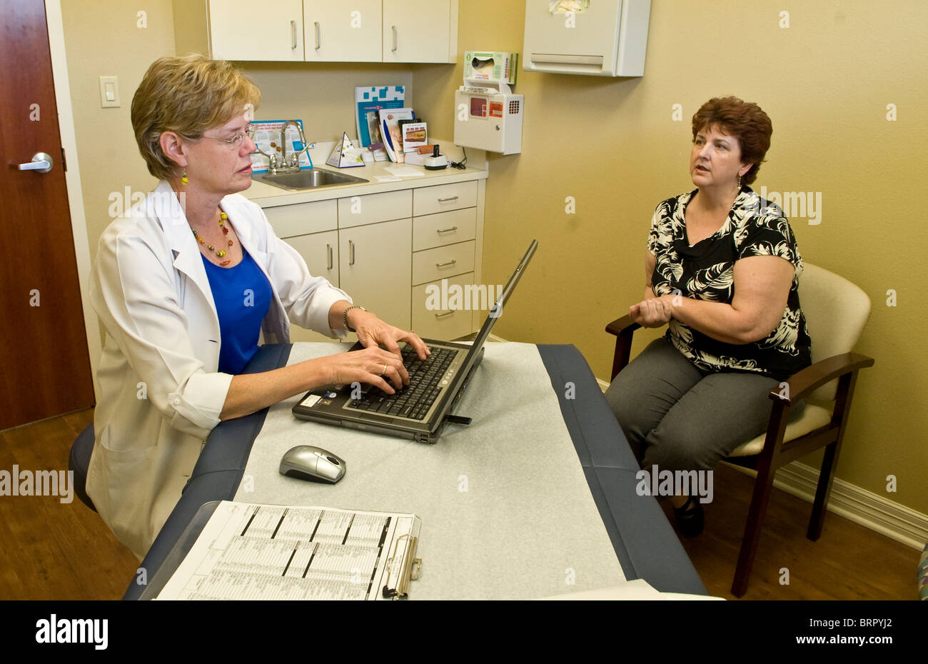 Female nurse practitioner types notes on laptop computer while