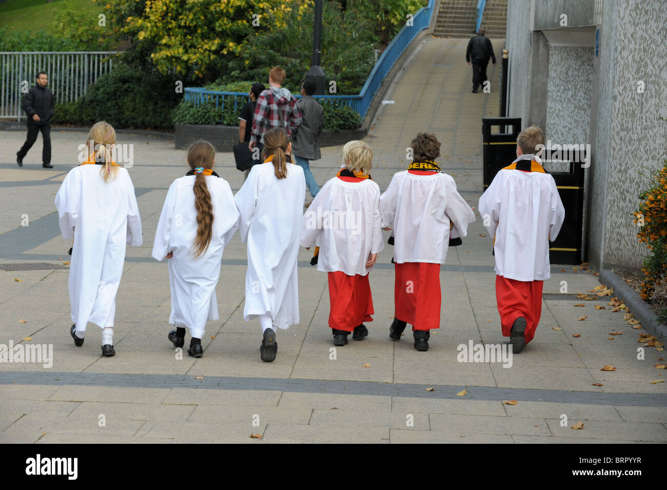 Six choristers, thee boys and three girls in their robes walking in a line towards a subway in Wolverhampton Stock Photo