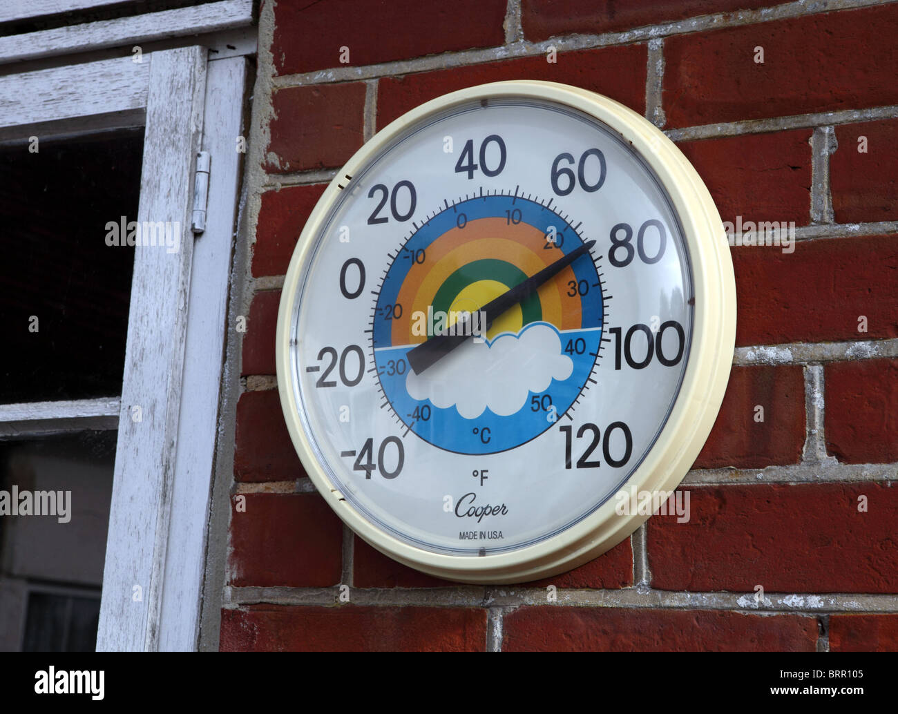 Colourful round thermometer on a garden wall Stock Photo