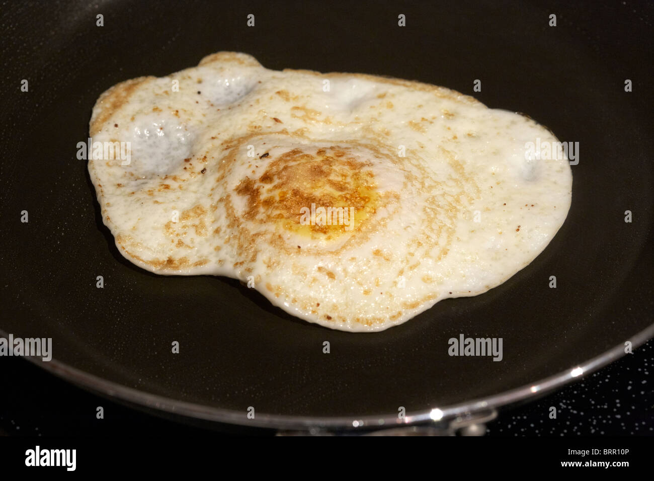 cooking an over easy egg in a frying pan Stock Photo