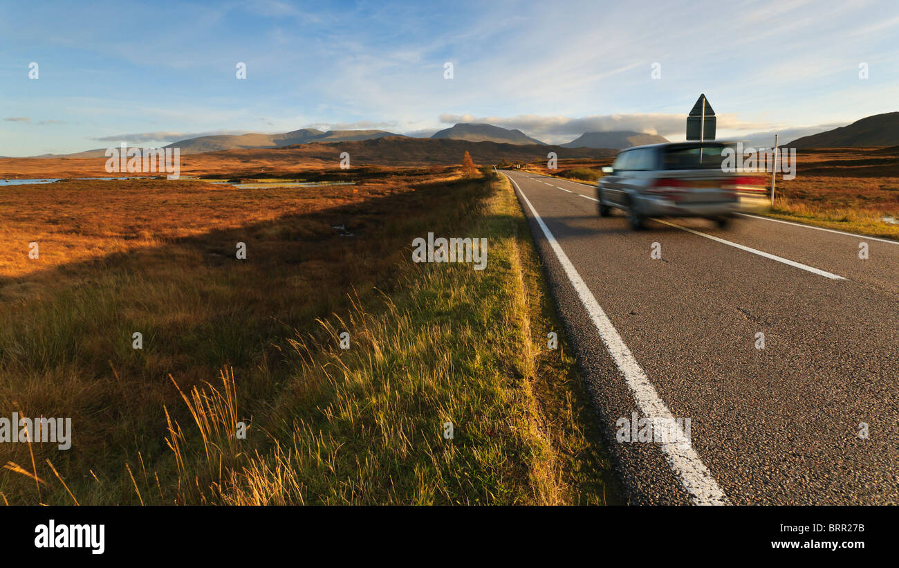 A car drives at speed along the road crossing Rannoch Moor Stock Photo