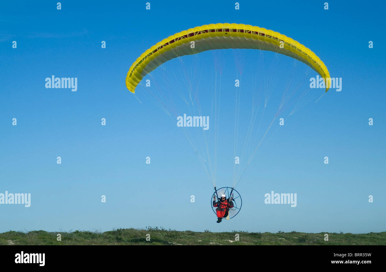 A motorized hang glider flying through the air Stock Photo