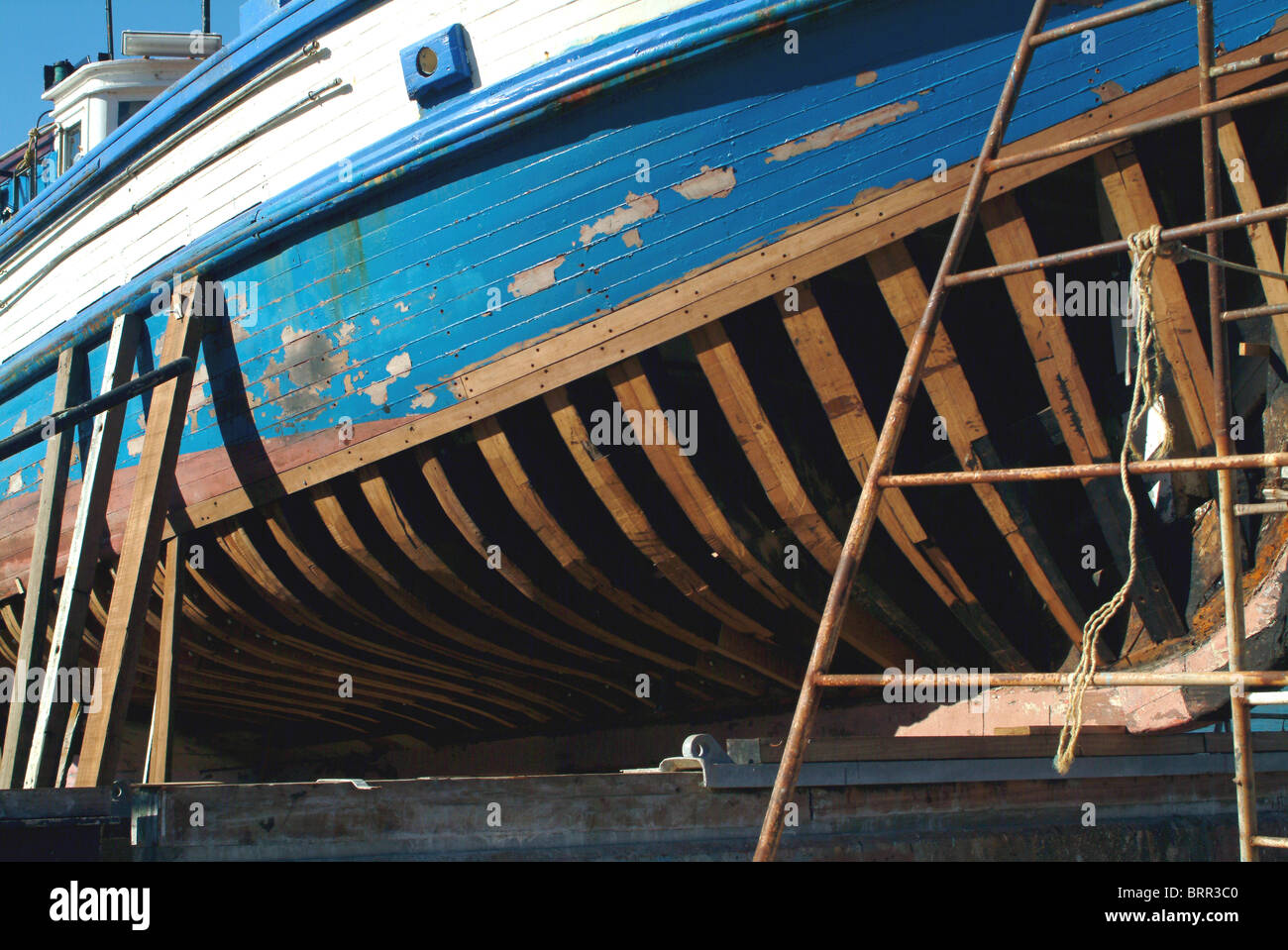 Wooden sailing boat in dry dock being repaired Stock Photo