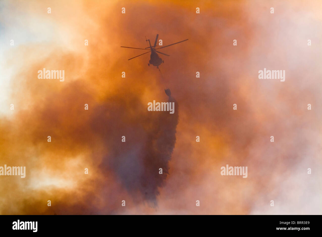 Helicopters fighting a mountain fire using water-bombs. Stock Photo