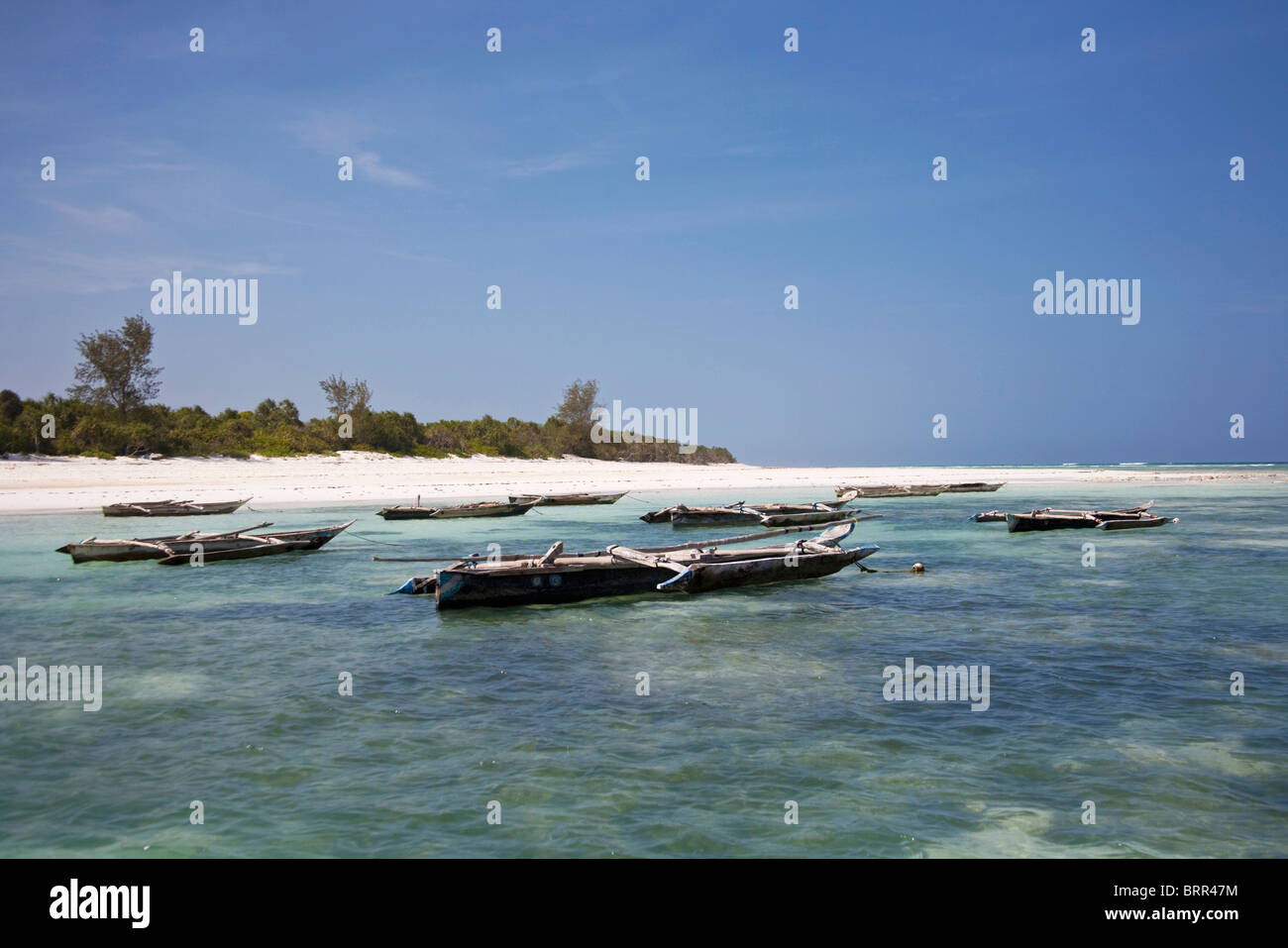 Beach scene with outrigger fishing boats moored in shallow water off Mnemba Island Stock Photo