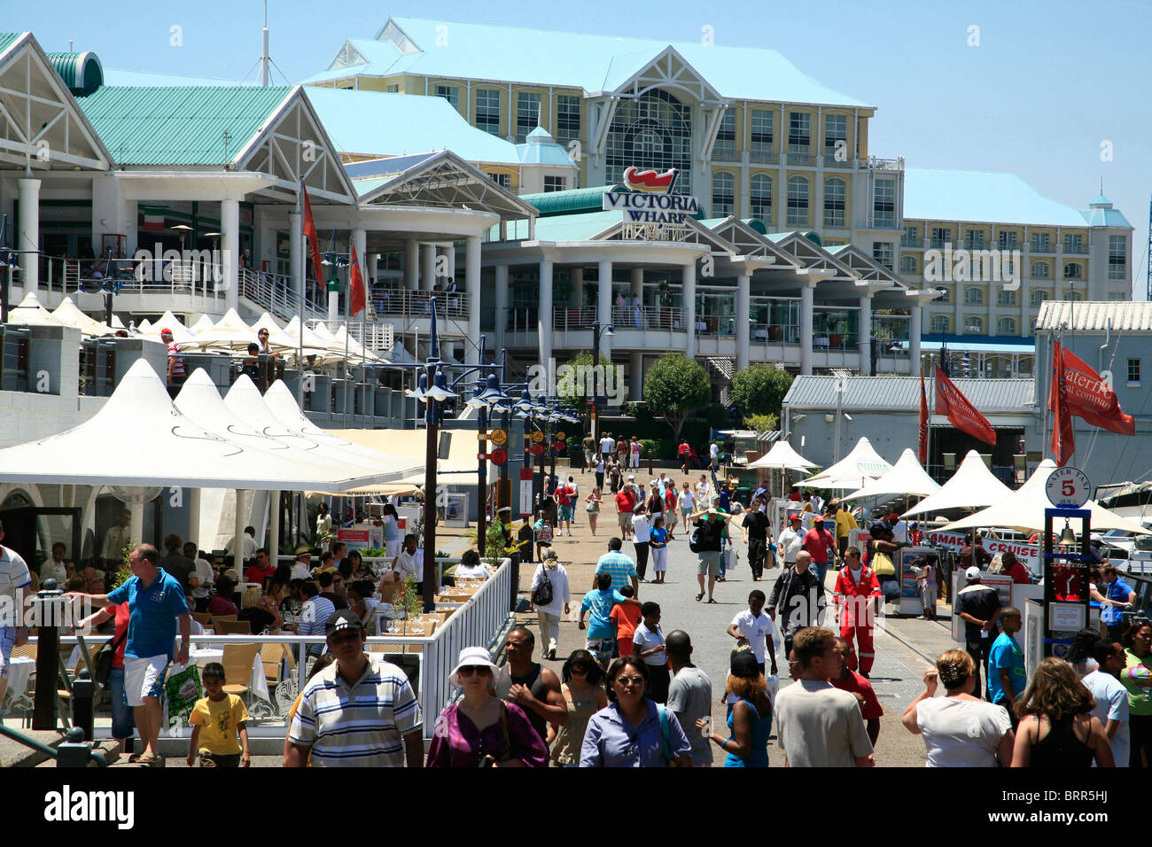 Shoppers walking along the pedestrian boulevard at the Victoria and Alfred Waterfront Stock Photo