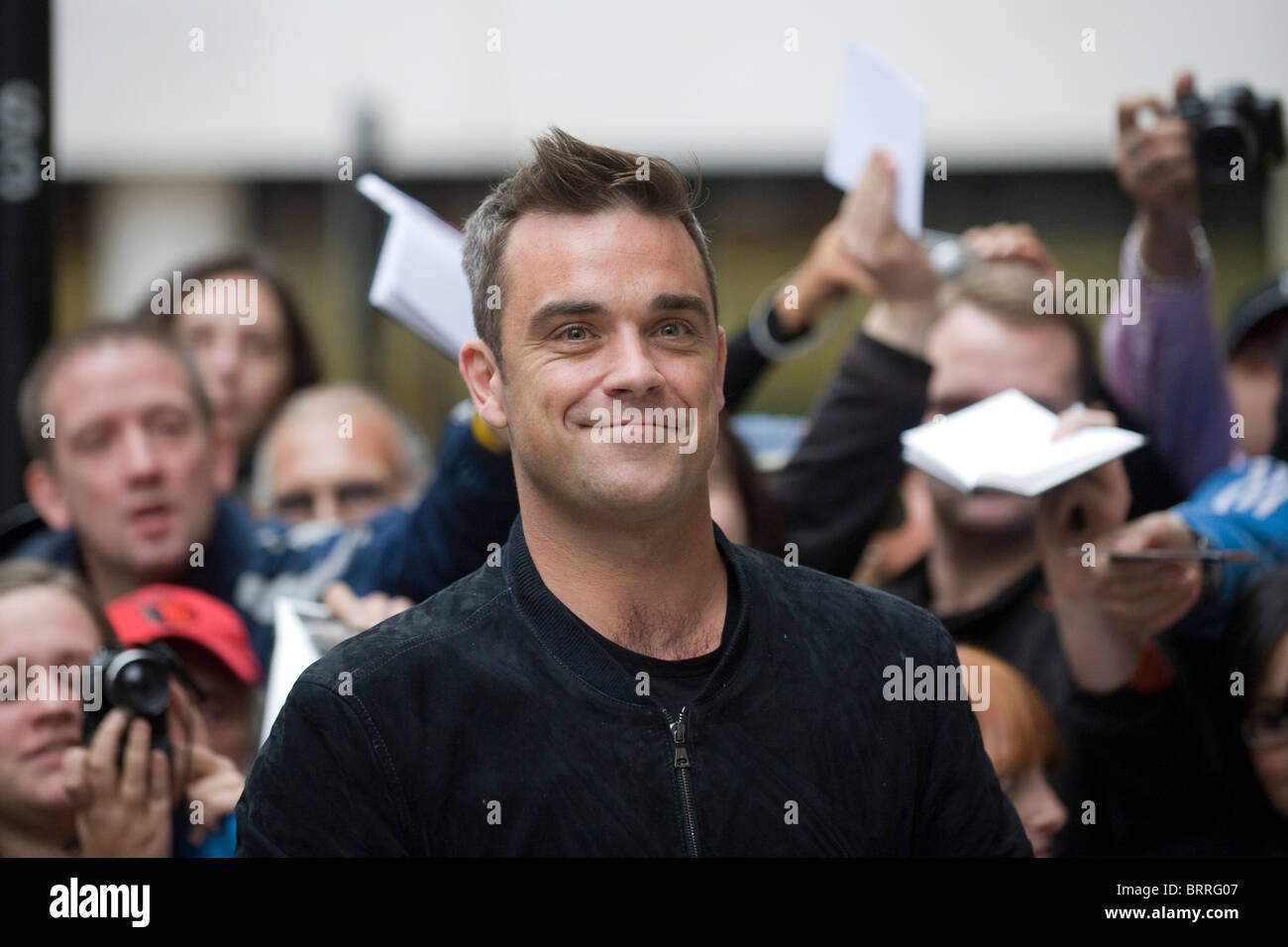 Robbie Williams arrives at Radio 2 interview with fans behind Stock Photo
