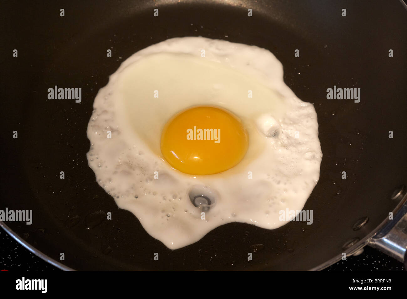 cooking a sunnyside up fried egg in a frying pan Stock Photo