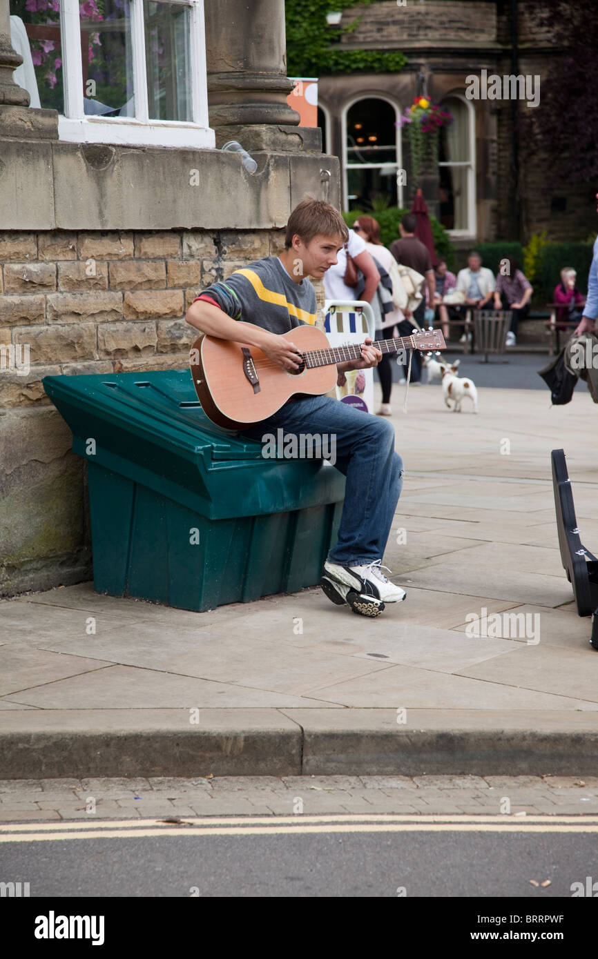 Young boy playing guitar/busking in Buxton town Derbyshire Peak