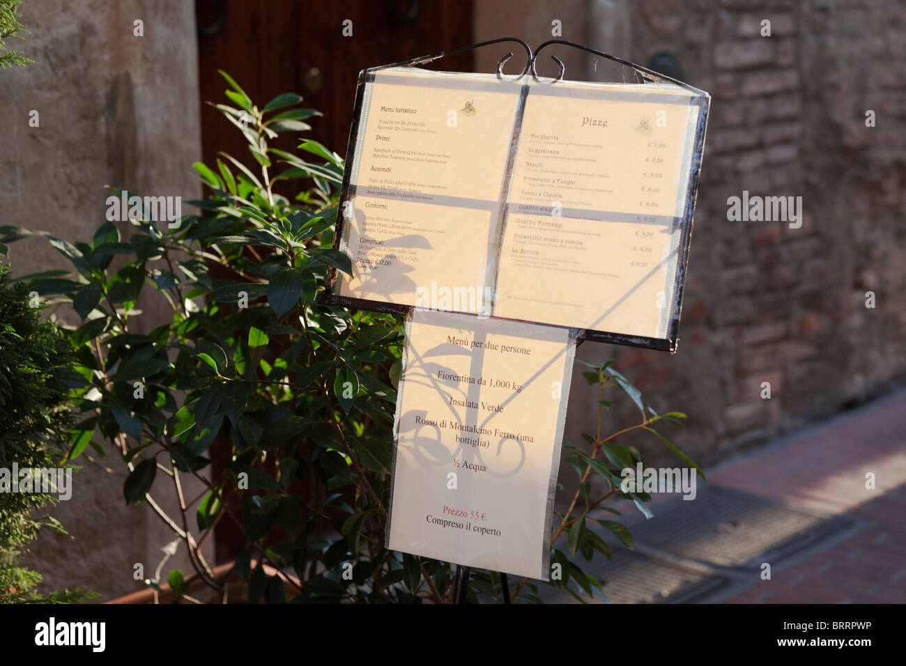 The evening sun back lights a menu board on display on a street outside a restaurant Stock Photo