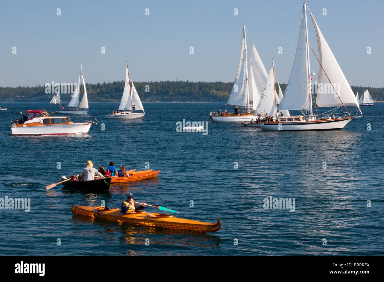 Large and small wooden sailboats sailing and kayakers kayaking in Wooden Boat Festival, Port Townsend, Washington, USA Stock Photo