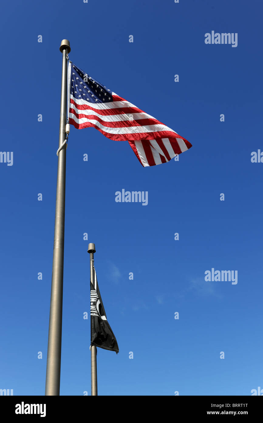The United States of American flag flies next to black POW/MIA flag over blue sky Stock Photo