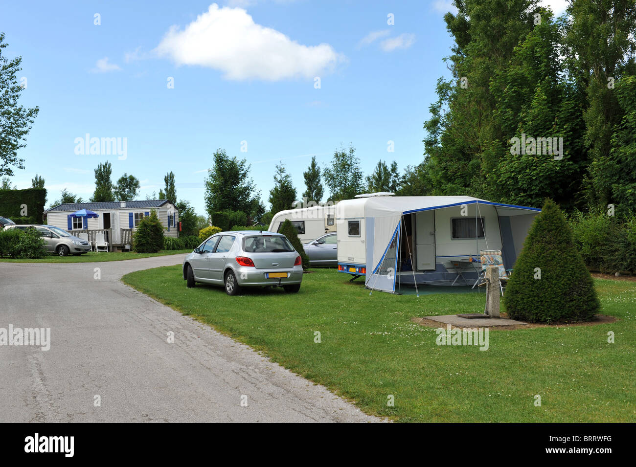 Touring caravans and a mobile home on a pleasant wooded caravan park campsite. Stock Photo