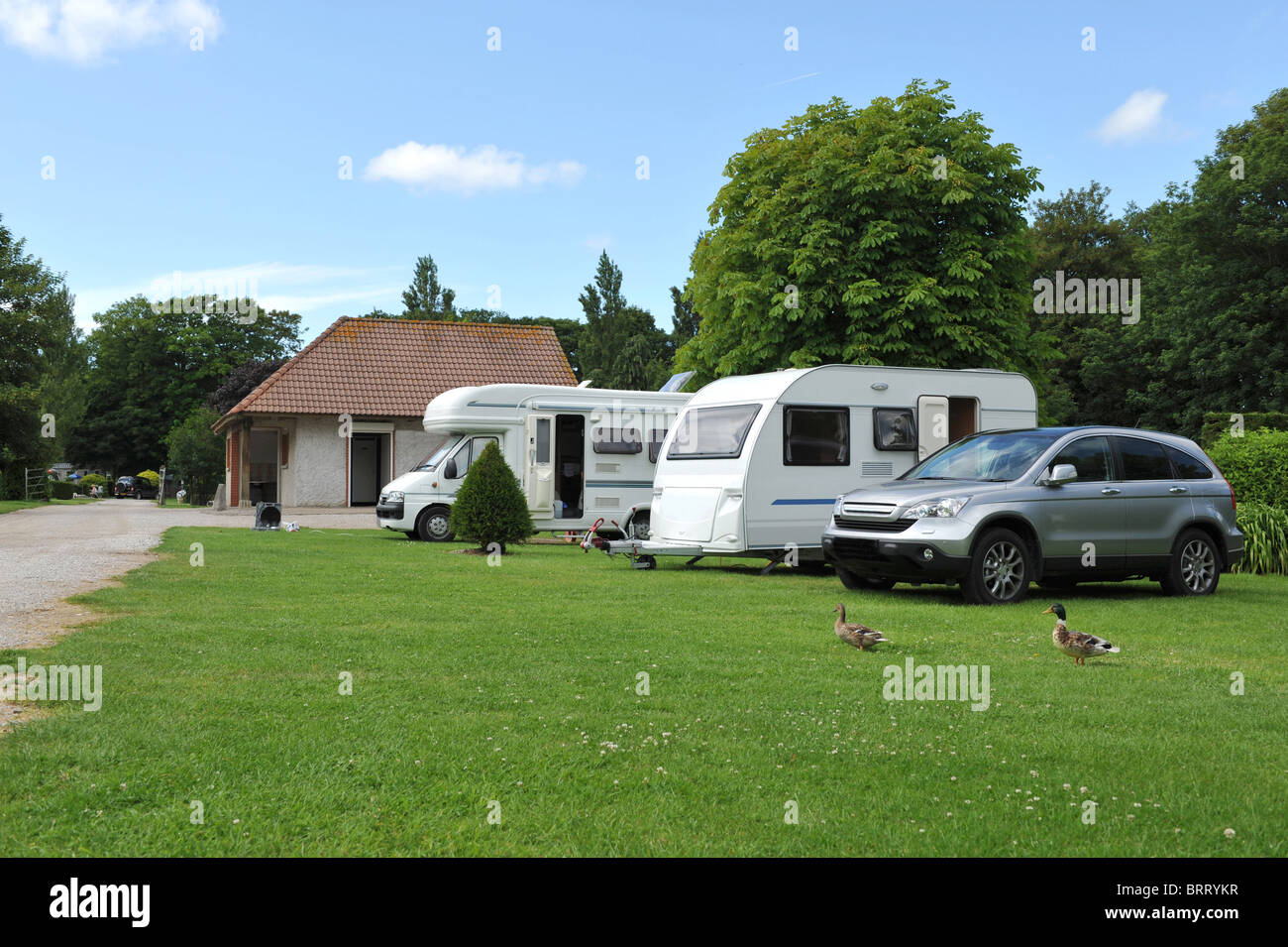 A motor home and a touring caravan all set up on a pleasant caravan park campsite. Stock Photo