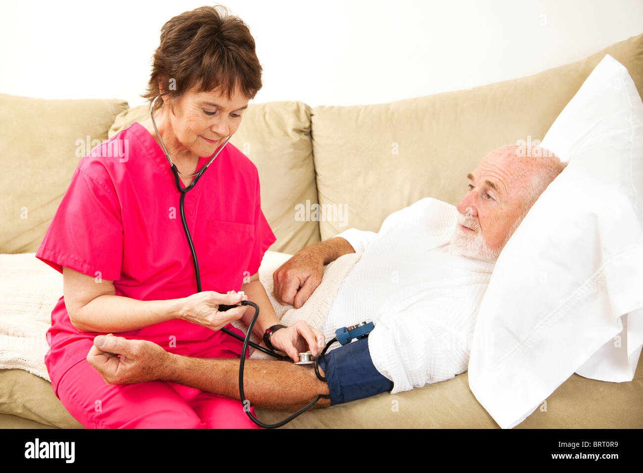 Friendly home health nurse taking the blood pressure of an elderly patient.  Stock Photo