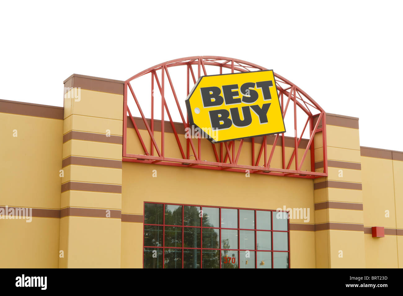 The front entrance and logo trademark sign for a Best Buy retail electronics store on a cloudy overcast day. Stock Photo