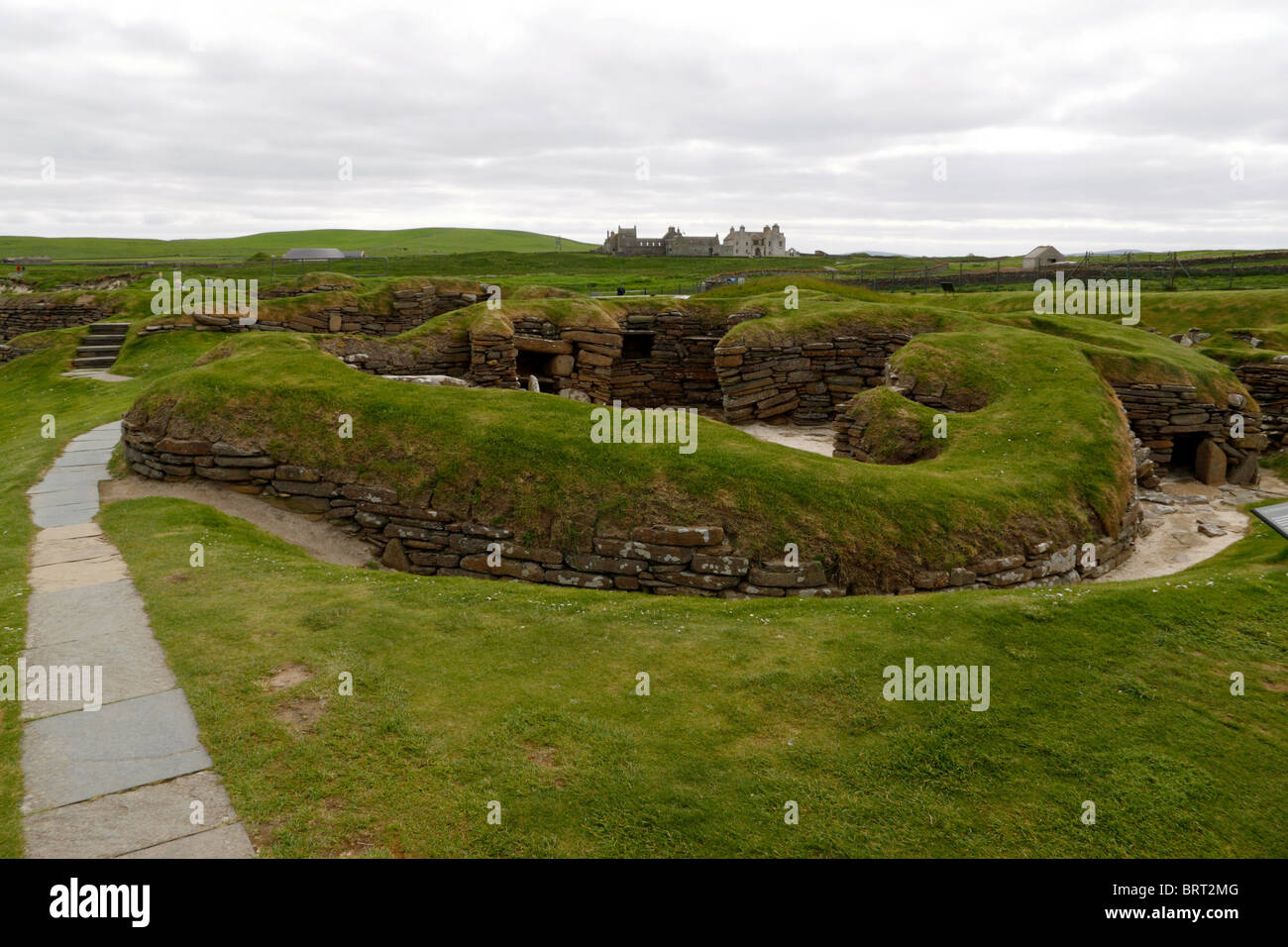 View of the Neolithic village of Skara Brae with Skaill House in background Stock Photo