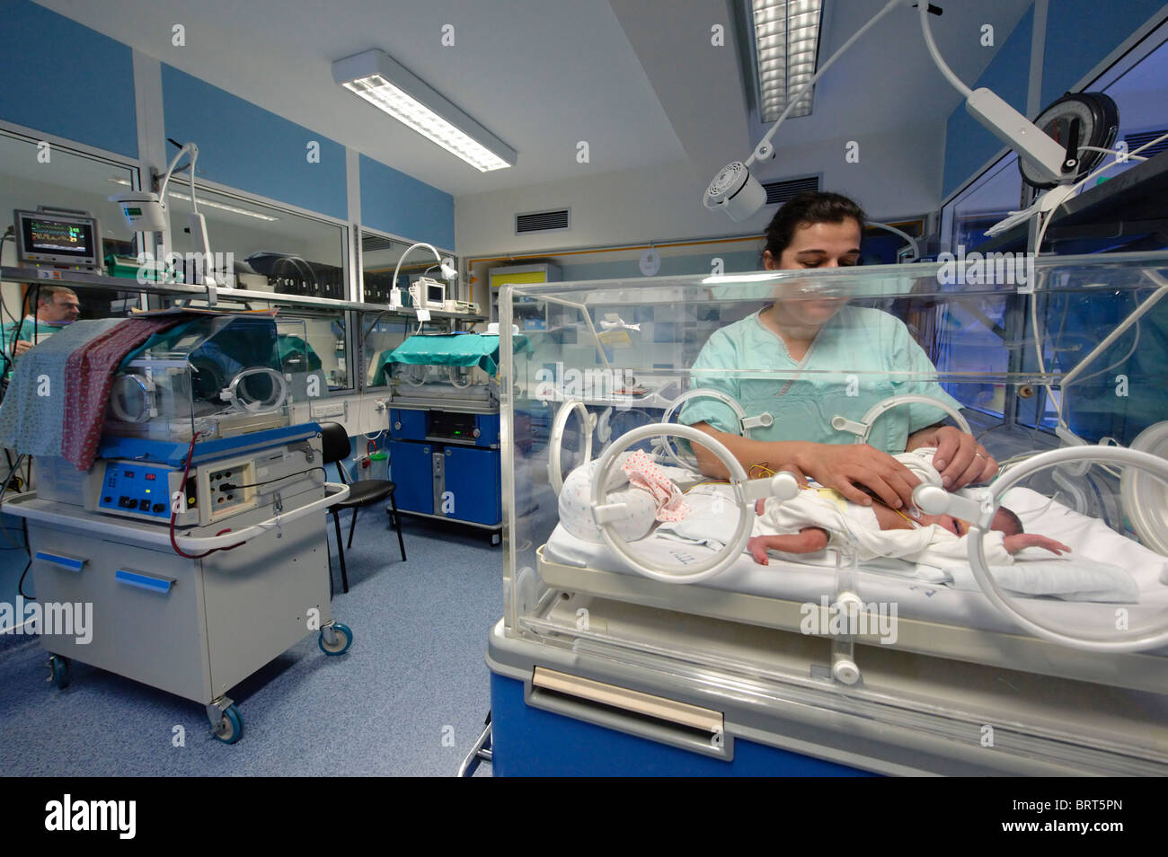 Female nurse tending premature baby in an incubator Stock Photo