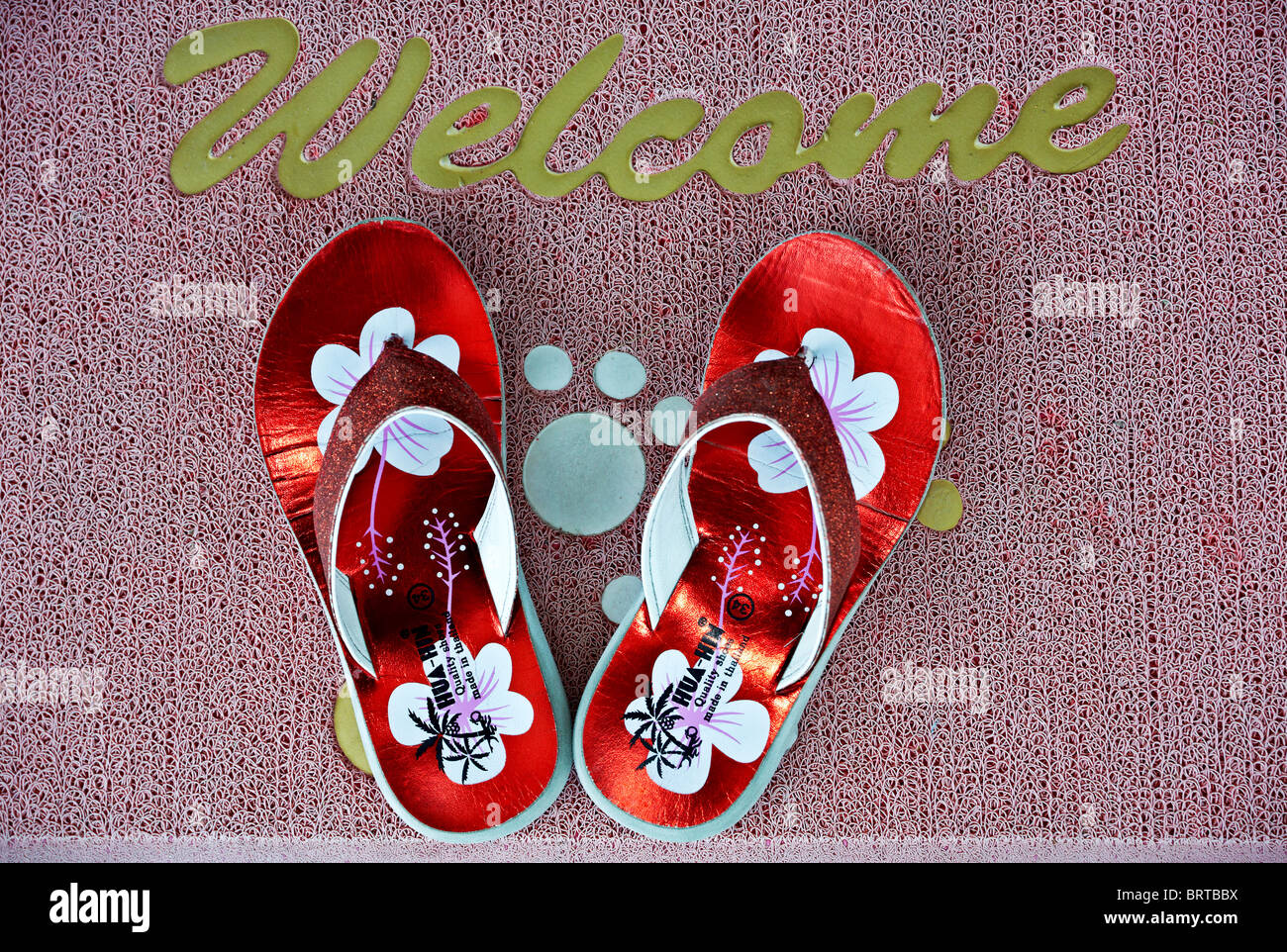 Brightly coloured flip flops on a home welcome door mat. Thailand S. E. Asia Stock Photo