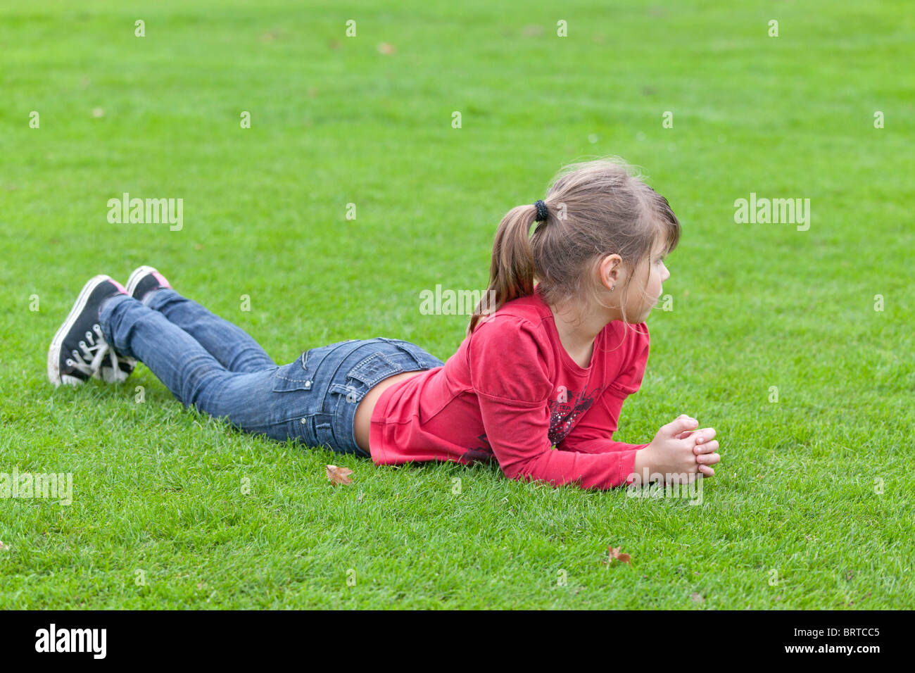 portrait of a little girl lying on a lawn Stock Photo - Alamy